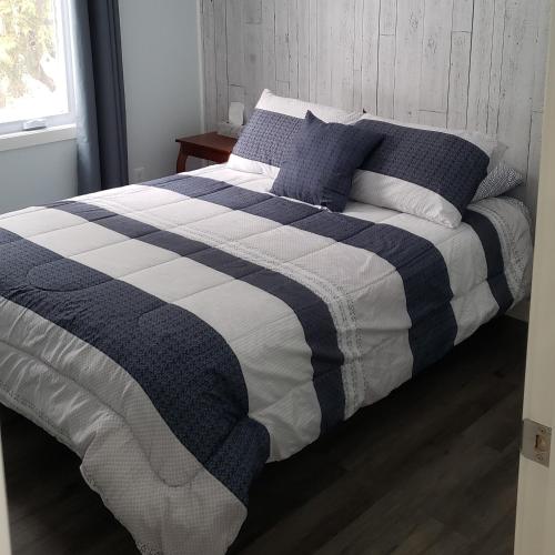 uma cama com um cobertor listrado azul e branco em Le Chalet Amical em Saint-Paulin