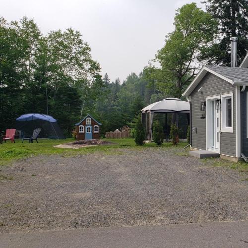 a campsite with a house and a tent at Le Chalet Amical in Saint-Paulin