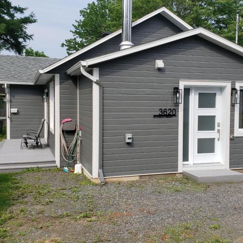 a gray garage with a door and a porch at Le Chalet Amical in Saint-Paulin