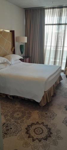 a large bed in a room with a large window at Al Khozama Executive Apartments in Riyadh