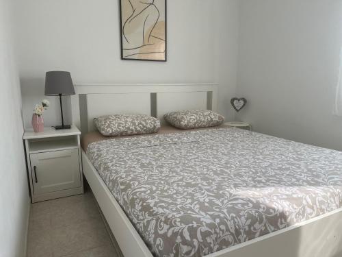 a white bedroom with a bed with two pillows on it at Pinezići apartman Niccole in Pinezici