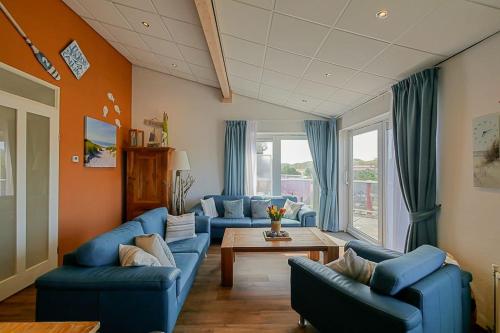 un salon avec des canapés bleus et une table dans l'établissement Appartement Celina - Residence Juliana Julianadorp aan Zee, à Julianadorp