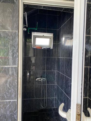 a shower in a bathroom with a black tiled wall at Victory Apartments in Sutomore