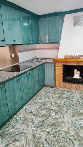 a kitchen with green cabinets and a fireplace at La Casa de los Tiles in Vélez Blanco