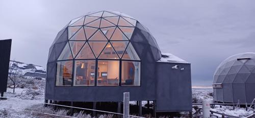 une maison en verre avec une fenêtre sur un champ enneigé dans l'établissement Dome with Stunning Glacier & Mountain Views, à Puerto Natales