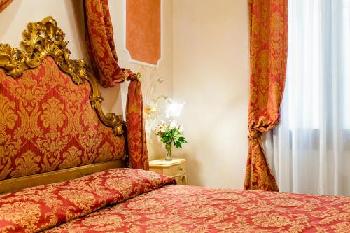 a bedroom with a bed with a red headboard and curtains at Hotel Al Vagon in Venice