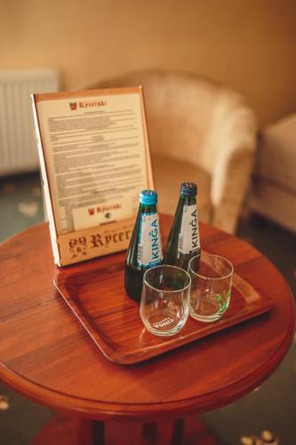 two bottles and glasses on a table with a laptop at Hotel Rycerski in Czeladź