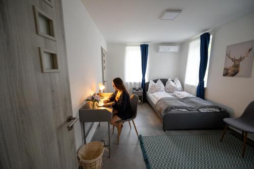 a woman sitting at a desk in a small room at Tótündér Vendégház in Levelek