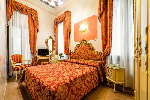 a bedroom with a bed with a red bedspread at Hotel Al Vagon in Venice