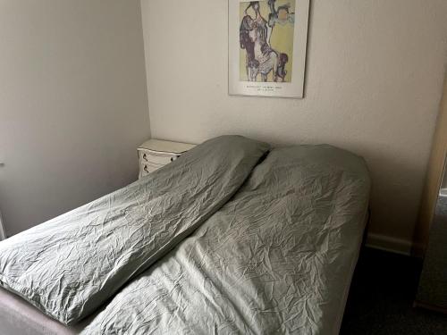a unmade bed in a bedroom with a picture on the wall at Udbyhøjvejens overnatning in Randers