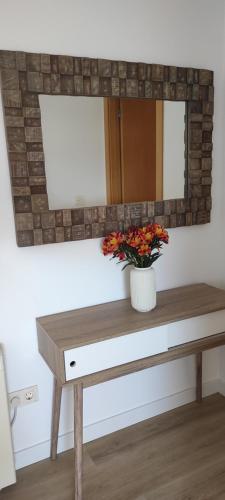 un tavolo con specchio e un vaso con dei fiori sopra di Amaral Xunqueiras a A Pobra do Caramiñal