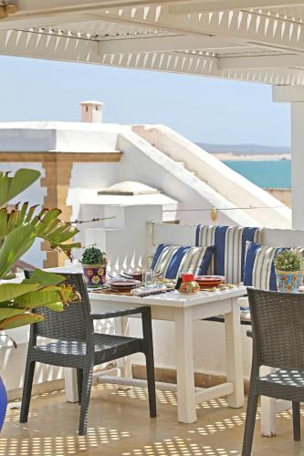 a dining room with a white table and chairs at Riad Dar L'Oussia & SPA in Essaouira