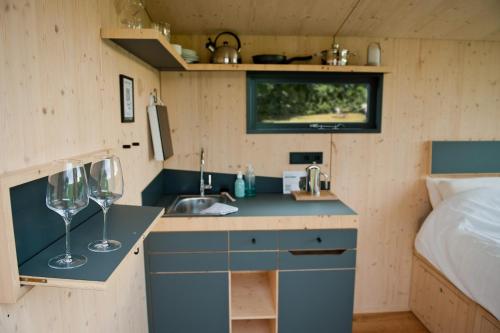 a small kitchen with a sink and two wine glasses at Sleep Space 01 - Green Tiny Spot Geltinger Bucht in Steinbergkirche