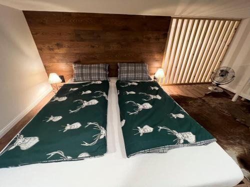 Una cama con edredón verde y almohadas. en "Hunter's Suite"- at the heart of Hartberg I Parking en Hartberg