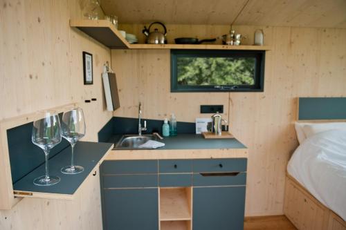 a small kitchen with a sink and two wine glasses at Sleep Space 02 - Green Tiny Spot Geltinger Bucht in Steinbergkirche
