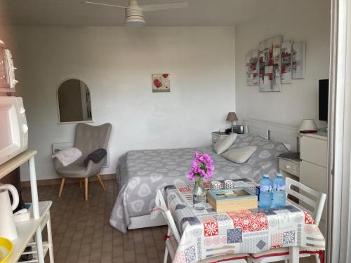 - une chambre avec un lit et une table fleurie dans l'établissement STUDIO CONFORT ET LUMINEUX avec LOGGIA ET PARKING, à Balaruc-les-Bains