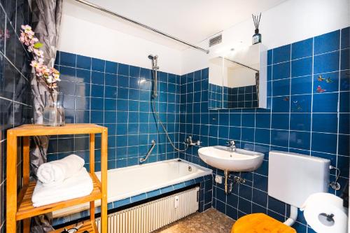 baño de azulejos azules con bañera y lavamanos en Hansa Apartment mit Schwimmbad, direkt am Hansapark, en Sierksdorf