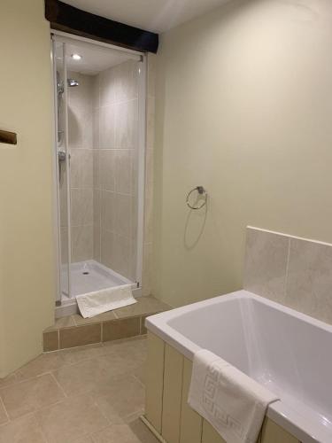 a white bathroom with a tub and a shower at Swallows Barn in Penrith