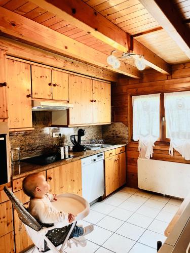 un bébé assis sur une chaise dans une cuisine dans l'établissement Entre Lac et Pistes de Ski, à Gérardmer