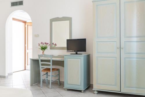 Zimmer mit einem Schreibtisch, einem TV und einer Tür in der Unterkunft Hotel Biderrosa in Cala Liberotto