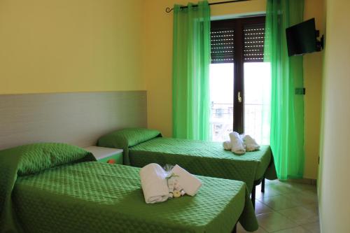 Zimmer mit 2 Betten und einem Fenster mit grünen Vorhängen in der Unterkunft Contedoro Living in Ariano Irpino