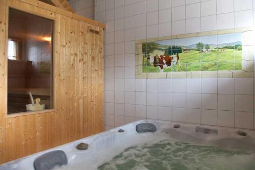 y baño con bañera y una foto de vacas. en Gîte l'essentiel en Arc-sous-Cicon