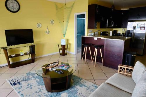 ein Wohnzimmer mit einem Sofa und einem Tisch sowie eine Küche in der Unterkunft Relaxing 1bed 1bath Villa In Downtown Red Hook! in Nazareth