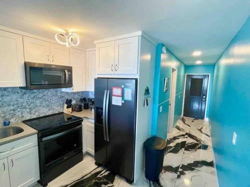 a kitchen with a black refrigerator and white cabinets at Luxury 2bed 2bath Condo In Downtown Red Hook in St Thomas