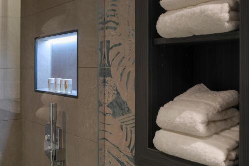 a bathroom with a mirror and a bunch of towels at SPREE. Hotel am Hafen in Lübbenau