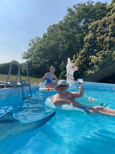 Un homme dans une piscine sur un pneumatique dans l'établissement Grange Bouton d Or Quiet countryside location, à Malleret-Boussac