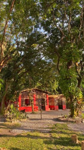 a red building with trees in front of it at Pousada Canto do sabiá Imbassaí in Imbassai