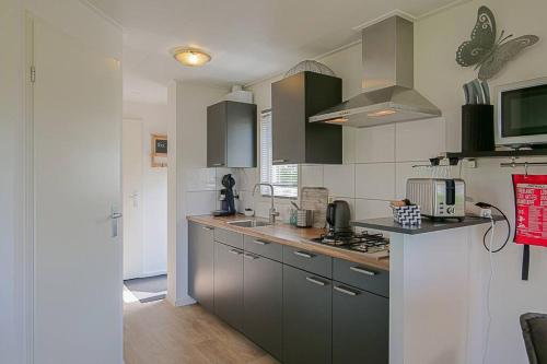 a kitchen with gray cabinets and a counter top at Chalet Riviéra - Camping De Watersnip Sint Maartenszee in Petten