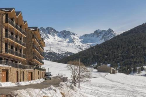 a ski lodge with a snow covered mountain in the background at HOLA ANDORRA - family apartment in Bordes d´Envalira