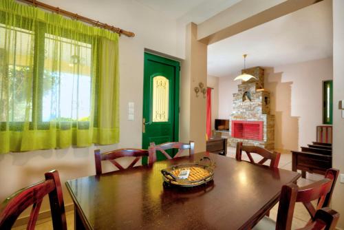 een eetkamer met een tafel en stoelen en een groene deur bij Villa Κτήμα Νικόλα in Likórrevma