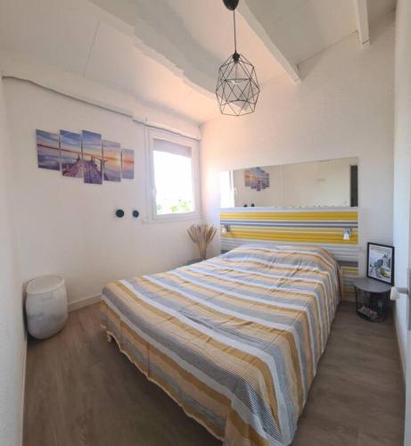 - une chambre avec un grand lit et une couverture rayée dans l'établissement Villa ou chambres sur l'Île des Marinas au Cap d'Agde, au Cap d'Agde