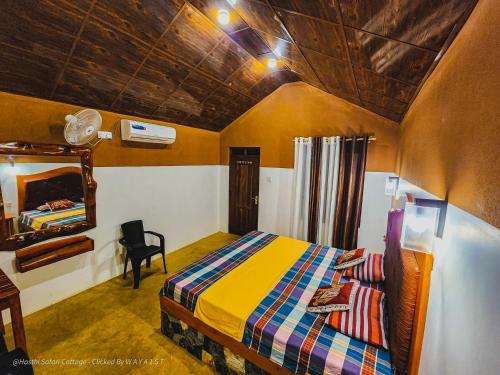 a bedroom with a bed and a mirror and a chair at Hasthi Safari Cottage in Udawalawe