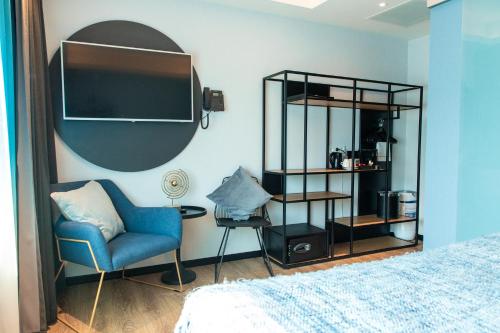 a bedroom with a bed and a chair and a shelf at Palace Hotel Zandvoort in Zandvoort