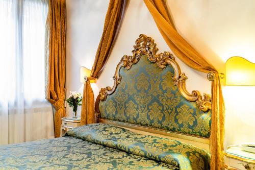 a bedroom with a bed with a blue and gold headboard at Hotel Al Vagon in Venice