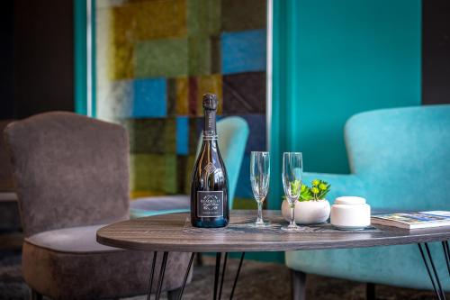 a bottle of wine sitting on a table with two glasses at Best Western Adagio Saumur in Saumur