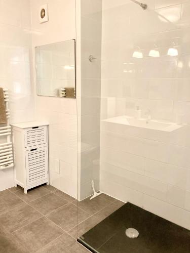 une salle de bain blanche avec un lavabo et un miroir dans l'établissement Grand Duplex climatisé avec terrasse face à la mer, à Sainte-Maxime