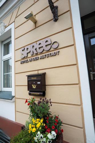 a sign on the side of a building with flowers at SPREE Hotel in der Altstadt in Lübbenau