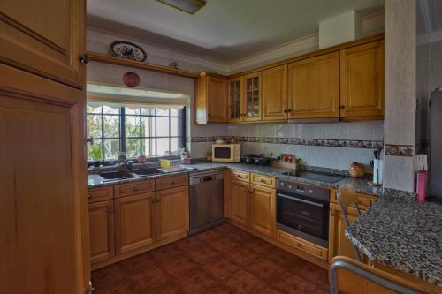 cocina con armarios de madera, fregadero y ventana en Quarto em Viana do Castelo, en Viana do Castelo