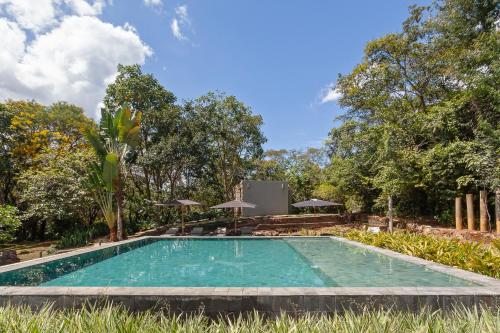a swimming pool in the middle of a yard with trees at Capim do Mato Pousada & Spa by L'Occitane in Serra do Cipo
