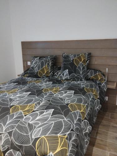 ein Bett mit einer schwarzen und gelben Bettdecke und Kissen in der Unterkunft La maison en bois in Monteils