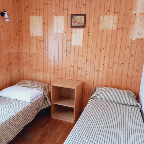 two twin beds in a room with wooden walls at APPARTAMENTO OLGA in Massimeno