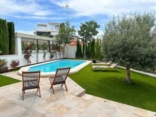 een achtertuin met een zwembad en twee stoelen bij Nice Nordic Style Villa 8 min from the beach. in El Campello