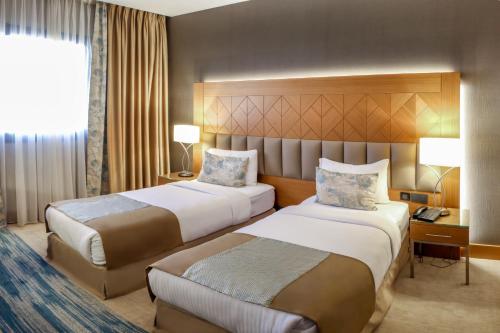 CheragaにあるSYM Hôtelのベッド2台と窓が備わるホテルルームです。