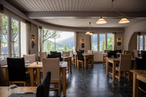 um restaurante com mesas, cadeiras e janelas em Hôtel les Flocons em Le Sauze