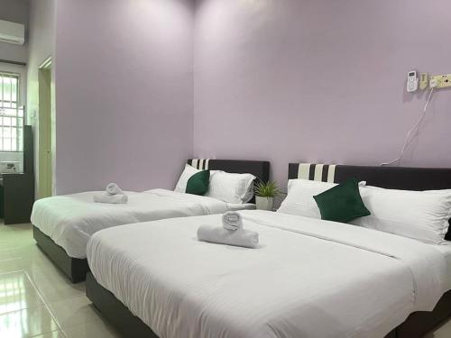 duas camas num quarto com branco e verde em JJ&KK Homestay em Taiping