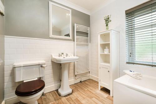 a white bathroom with a toilet and a sink at End Cottage in Fakenham